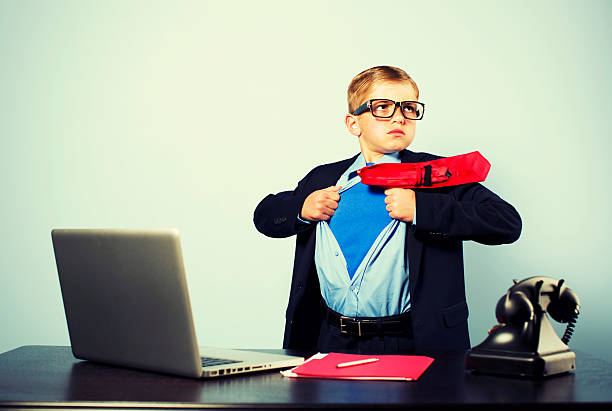 Boy in Office Dressed as Superhero at Laptop This young office worker is ready to save the day for your business.  cross processed stock pictures, royalty-free photos & images