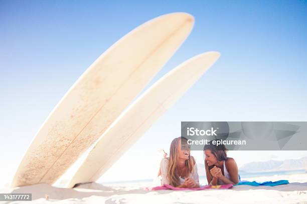 Dos Chicas Surfista Y Adolescente Sonriente Gossiping En La Playa Foto de stock y más banco de imágenes de Surf