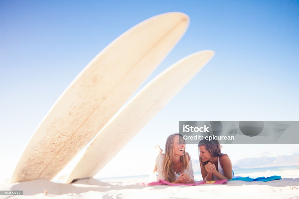 Due ragazze adolescenti di ridere e spettegolare sulla spiaggia - Foto stock royalty-free di Surf