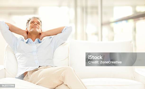 Man With Hands On His Neck Relaxing On White Sofa Stock Photo - Download Image Now - Serene People, Tranquil Scene, Men