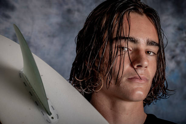 Young man prepares to go surfing with his surfboard.