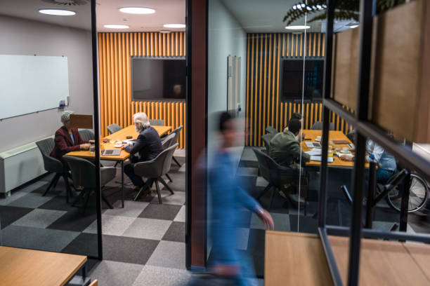 Motion blur of a businessman walking quickly through busy modern office lobby.