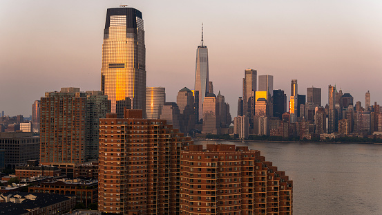 Paulus Hook in Jersey City with Portside Towers apartments and Goldman Sachs Tower. Remote view of Lower Manhattan over the Hudson River at sunset.