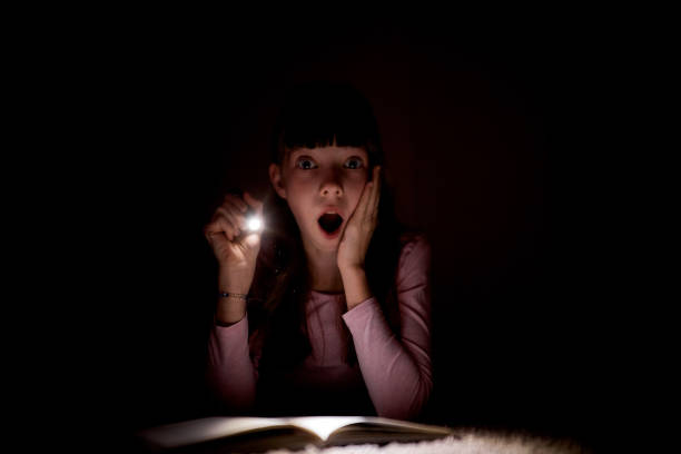 istock little girl is reading a book with a flashlight in a dark room at night 1431801183