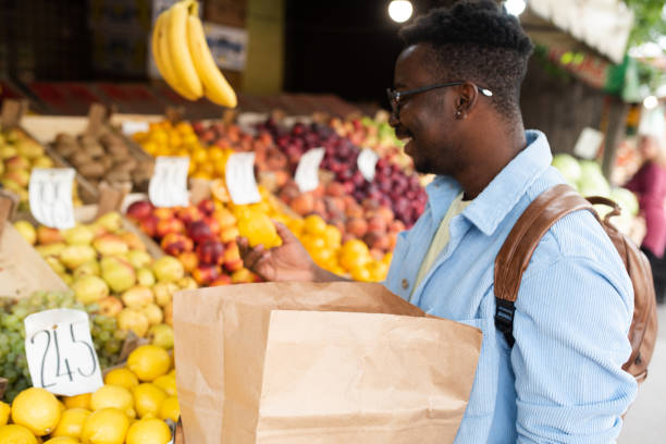 istock Young man buys fruit at the market 1431802101