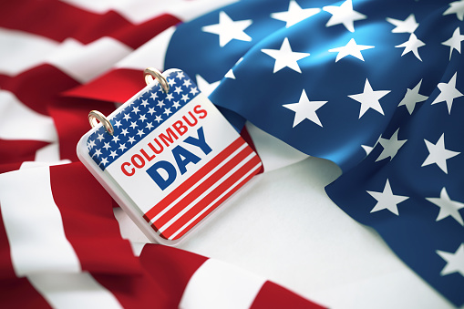 Columbus Day written calendar over rippled American flag. High angle view and horizontal composition.
