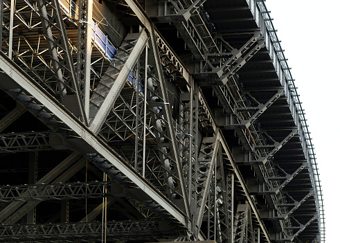 Close up from beneath and to the side of the Sydney Harbour Bridge. Shot shows the complex steelwork and part of the arch curve