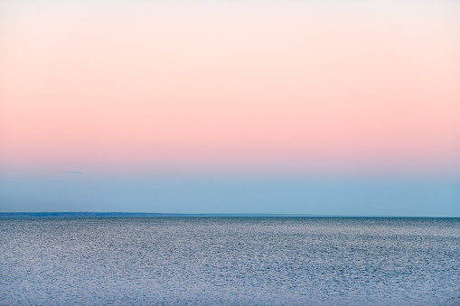 Atmospheric romantic pink red sea sunset sky above blue quiet water, minimalistic peaceful seascape, beautiful background copy space. Pinkish sky above Azov sea horizon, Rostov on Don region in Russia
