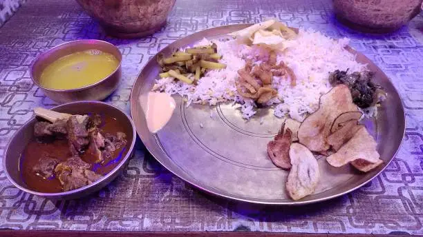 traditional nepali thali served on a brass plate with rice,meat curry, lentils and other side dishes. staple food for nepali culture.