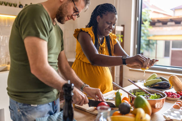 couple cuisine ensemble à la maison - human pregnancy photos et images de collection