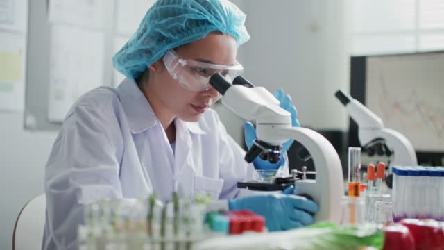 Microbiologist Looking at a Lab-Grown Cultured Vegan Meat Sample in a Microscope
