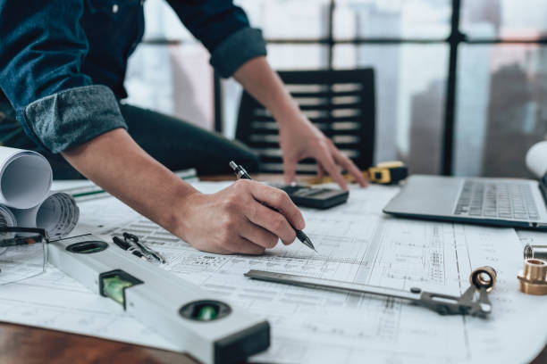 istock Engineering working with drawings inspection and writing on the office desk and Calculator, triangle ruler, safety glasses, compass, vernier caliper on Blueprint. Engineer, Architect, Industry and factory concept. 1431871847