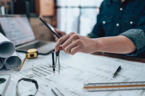 istock Engineering working with drawings inspection and writing on the office desk and Calculator, triangle ruler, safety glasses, compass, vernier caliper on Blueprint. Engineer, Architect, Industry and factory concept. 1431872485