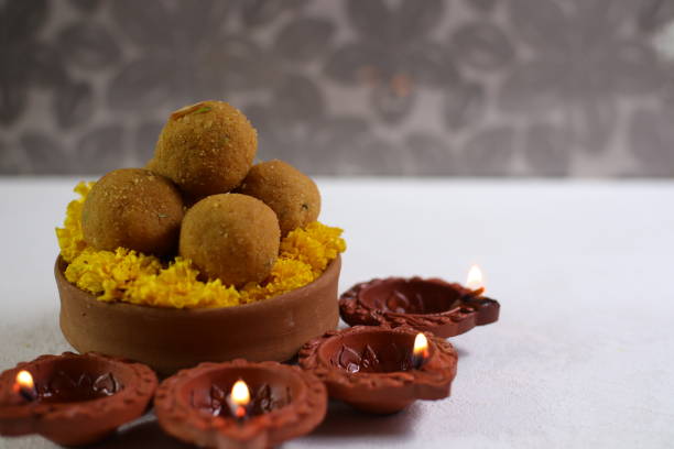 istock Diwali Rangoli using Diya, flowers and Besan Laddu over white background, selective focus 1431872503