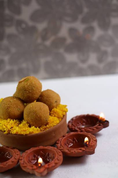 istock Diwali Rangoli using Diya, flowers and Besan Laddu over white background, selective focus 1431872567