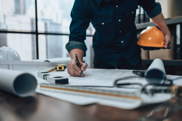 istock Engineering working with drawings inspection on the office desk and Calculator, triangle ruler, safety glasses, compass, vernier caliper on Blueprint. Engineer, Architect, Industry and factory concept. 1431872693