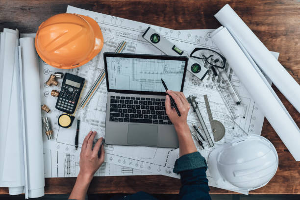 istock Engineering working with drawings inspection on laptop  in the office and Calculator, triangle ruler, safety glasses, compass, vernier caliper on Blueprint. Engineer, Architect, Industry and factory concept. 1431872773