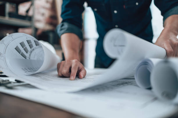 istock Engineering working with drawings inspection on the office desk and Calculator, triangle ruler, safety glasses, compass, verniear caliper on Blueprint. Engineer, Architect, Industy and factory concept. 1431873973