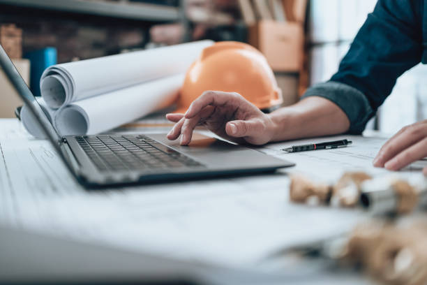 ingeniería trabajando con inspección de dibujos en computadora portátil en la oficina y calculadora, regla triangular, gafas de seguridad, brújula, pinza vernier en blueprint. ingeniero, arquitecto, industria y concepto de fábrica. - solar de construcción fotografías e imágenes de stock