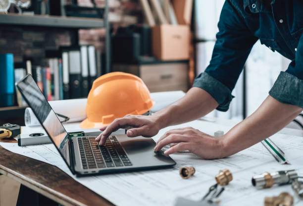 istock Engineering working with drawings inspection on laptop  in the office and Calculator, triangle ruler, safety glasses, compass, vernier caliper on Blueprint. Engineer, Architect, Industry and factory concept. 1431874955