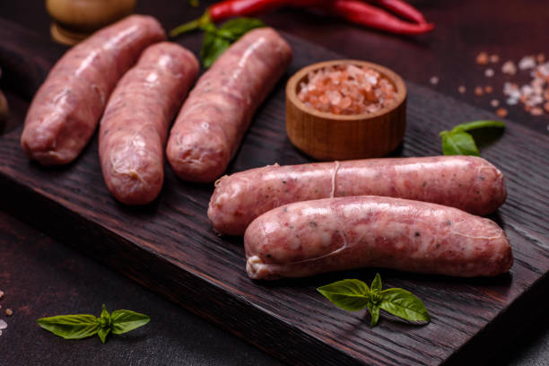 istock Raw sausages with ingredients on a cutting board on a dark concrete background with copy space 1431875073