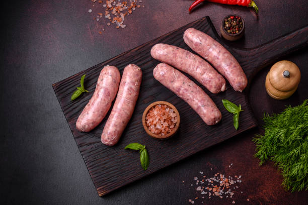 istock Raw sausages with ingredients on a cutting board on a dark concrete background with copy space 1431875076