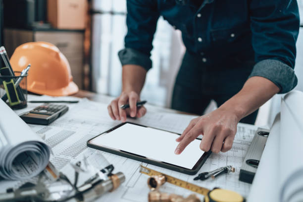 istock Engineering working with drawings inspection on tablet in the office and Calculator, triangle ruler, safety glasses, compass, vernier caliper on Blueprint. Engineer, Architect, Industry and factory concept. 1431875544