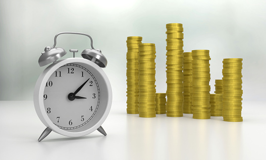 White Alarm Clock and coins on gray background. Time is money concept.