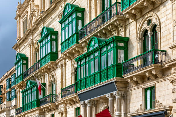Fragment of the building's facade with traditional wooden ornate balconies painted in green in Valletta, Malta.