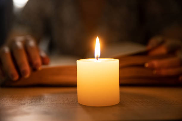 Reading a book by candle at night stock photo