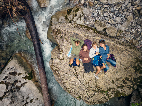 Aerial drone view of a family hiking by the river in the Alps - Tyrol, Austria. Mother and three teenagers are lying on backs on a boulder in the beautiful mountain river. They are relaxing and listening to the sound of flowing water.
DJI Mini 3 Pro