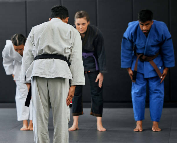 Fitness, strength and respect between karate trainer leading a class, bow and greeting martial arts student at a dojo or studio. Diverse group training and learning self defense, speed and endurance fitness, fuerza y respeto entre entrenador de karate dirigiendo una clase, arco y saludando a un estudiante de artes marciales en un dojo o estudio. entrenamiento grupal diverso y aprendizaje de habilidades de defensa personal y resistencia