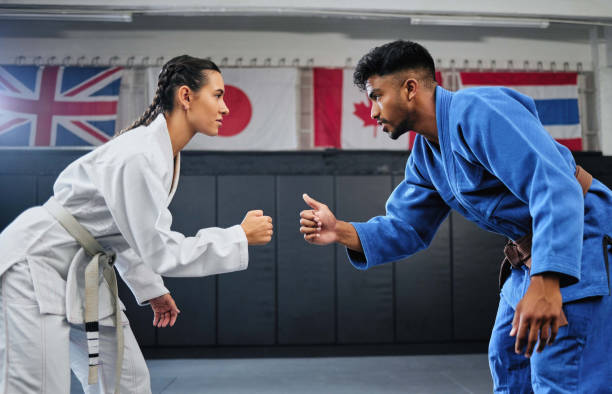 istock Karate, mma and fitness with a teacher and student learning, training and doing a workout for exercise, sport and health. Man and woman in fight, combat or self defense class in a gym studio 1431895938