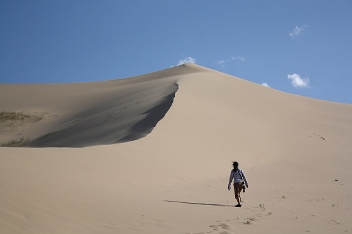 Walking alone along the Khongor Sand Dunes, Gobi Desert, Umnugovi province, Mongolia. The desert is desolate and windy. It is freezing during the long winter months from October to April. Nomads and livestock live out their nomadic lives around the sand dunes.