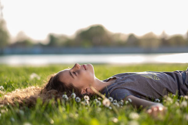 A little girl is lying on the grass and looking at the sky