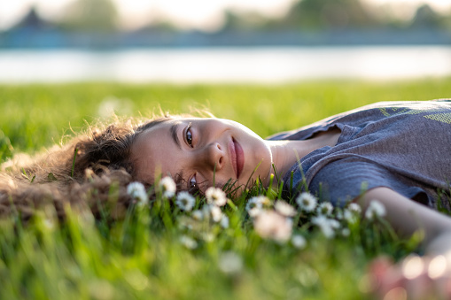A little girl is lying on the grass and looking at the camera
