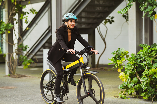 Portrait of a woman wearing protective helmet riding e-bike to work.