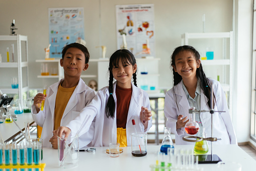 Students smile at camera while conducting a science experiment
