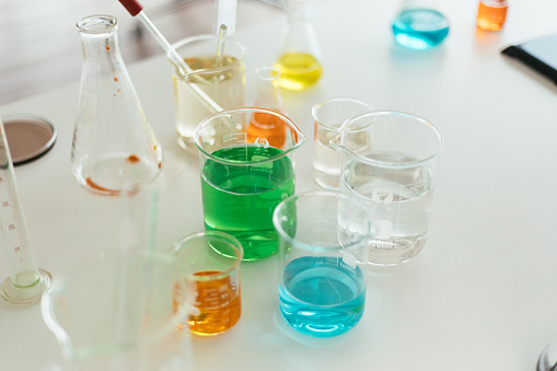 hand of scientist holding flask with lab glassware in chemical laboratory background, science laboratory research and development concept