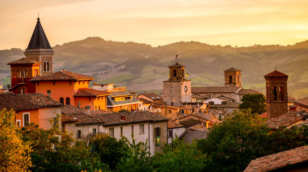 A suggestive sunset light envelops the roofs and bell towers of a medieval village in Umbria in central Italy A suggestive sunset light warms the roofs and the skyline of Gualdo Tadino, a medieval town near Gubbio, in the Italian region of Umbria. An important city since Roman times, Gualdo Tadino rises along the ancient consular Via Salaria, traced by the Romans. Its history runs throughout the Middle Ages and, despite having been partially destroyed and sacked numerous times and placed under the dominion of Perugia, this ancient Umbrian center still retains its medieval charm. The Umbria region, considered the green lung of Italy for its wooded mountains, is characterized by a perfect integration between nature and the presence of man, in a context of environmental sustainability and healthy life. In addition to its immense artistic and historical heritage, Umbria is famous for its food and wine production and for the high quality of the olive oil produced in these lands. Image in 16:9 and high definition format. gualdo tadino stock pictures, royalty-free photos & images