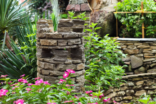 istock Decorative tower and stone wall, elements of landscape design and pink periwinkle or catharanthus. 1431909437