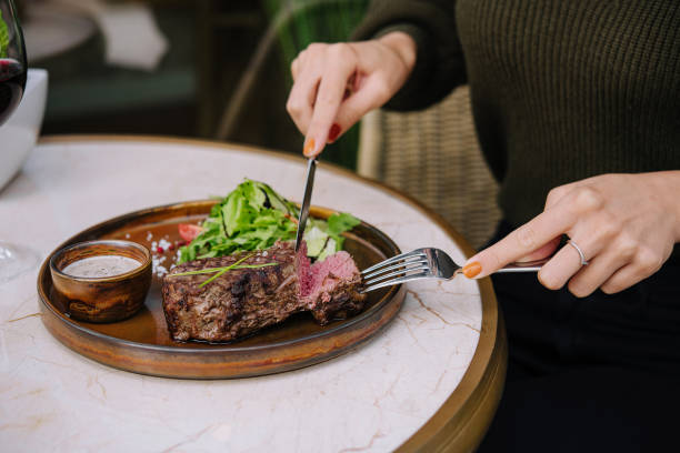 mãos femininas em um restaurante na mesa corte carne striploin bife - steak meat strip steak restaurant - fotografias e filmes do acervo