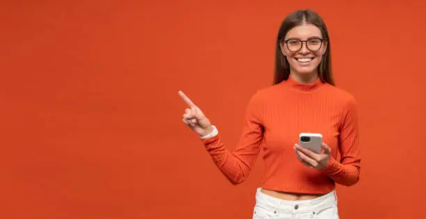 Photo of Woman office worker pointing at orange copy space background advertising business app