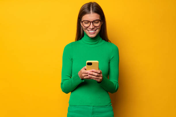 istock Woman office manager using phone during break at work chatting with her friend on yellow background 1431911064