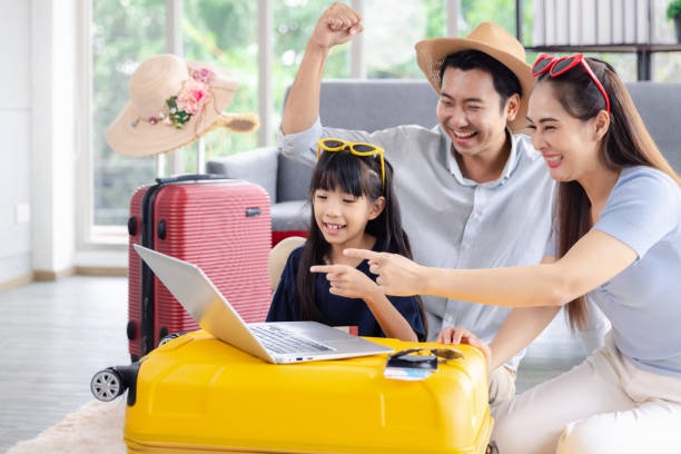 Young happy family asian father mother and daughter happy exciting preparing luggage suitcase booking ticket and hotel for vacation holiday travel trip stock photo