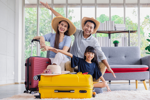 Young happy family asian father mother and daughter happy exciting preparing luggage suitcase booking ticket and hotel for vacation holiday travel trip