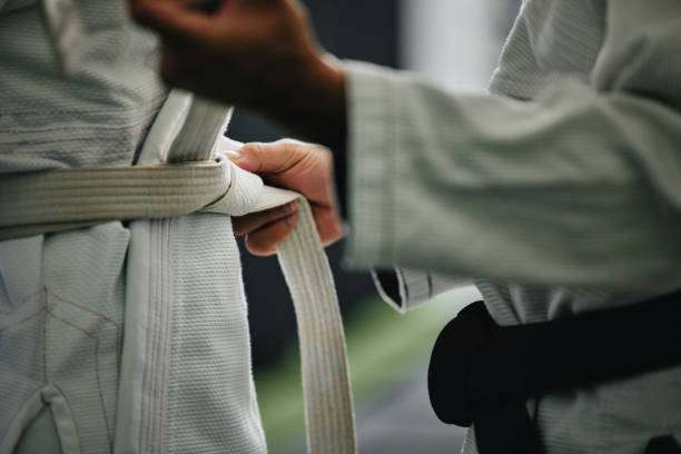 karate learning, training and workout of a sport student and coach getting ready for a fight class. defense expert hands tie a belt in a dojo, workout studio or wellness club about to work on fitness - karate judo belt aikido imagens e fotografias de stock