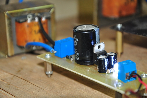 black electrolytic capacitor and regulator IC in the voltage converter circuit, which is connected to a 3 ampere transformer