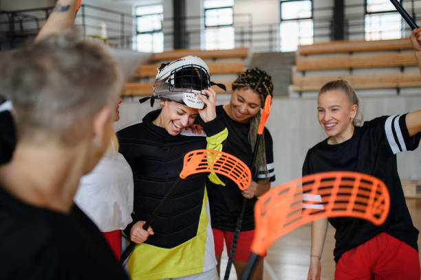 Group of young and old cheerful women, floorball team players, in gym cebrating victory. stock photo