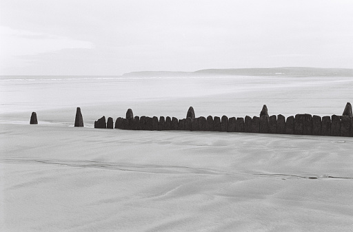 Bleak day on the beach with an outline of an old weathered groyne, 35mm film, North Devon